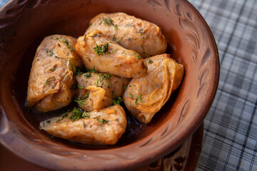 Stuffed cabbage leaves, cabbage rolls, and dolma in a clay pot, served with sour cream. Cabbage wraps. Chow Farsi, dolma, sarma, cabbage rolls, or golabki. Flat lay, arrangement, overhead.