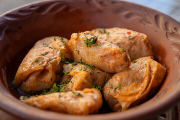 Stuffed cabbage leaves, cabbage rolls, and dolma in a clay pot, served with sour cream. Cabbage wraps. Chow Farsi, dolma, sarma, cabbage rolls, or golabki. Flat lay, arrangement, overhead.