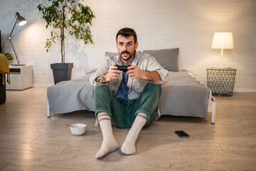 Young man playing video game with wireless controller