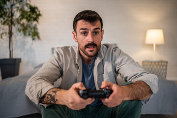 Young man playing video game with controller at home
