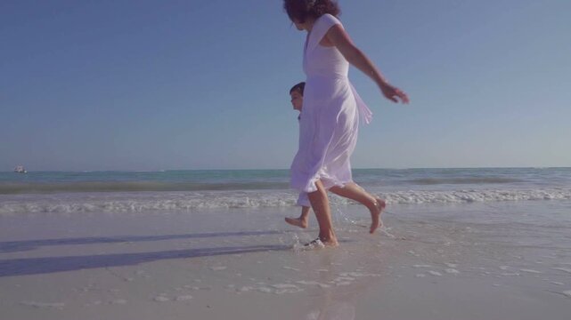 Mother Running with Young Son in Ocean Waves at Sunset in the Florida Keys