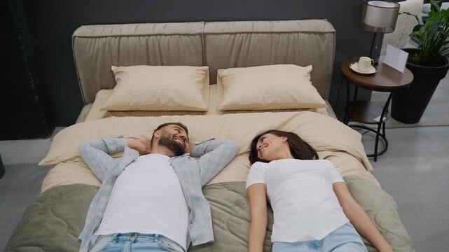 Happy couple choosing and testing a new comfortable bed