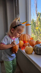 A child decorates pumpkins on a windowsill for the autumn holidays of Halloween and Thanksgiving.