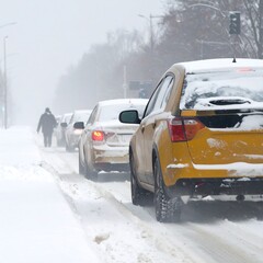 Cars lined up on a snowy city street during a blizzard.