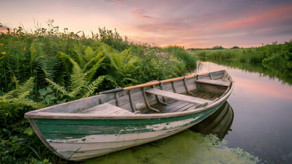 Obraz premium Sunset Over Riverbank Showcasing Weathered Teal Rowboat, Emerald Foliage, and Soft Pastel Hues - landscape art