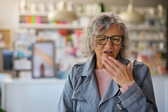 Ill senior woman coughing in pharmacy. - Powered by Adobe