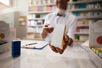 Close up of African American pharmacist holding medicine box in a pharmacy.