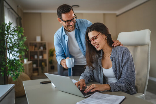 Couple remote working from home office using laptop - Powered by Adobe