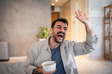 Happy man waving, eating breakfast, greeting cheerfully