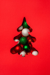 Christmas tree shape filled with red, green, and white glitter baubles on a bright red background.