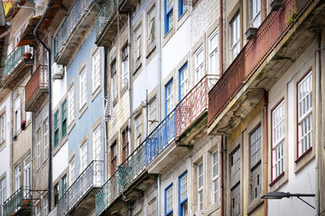 A tight view of lived-in Porto residential facades. Highlights the charming decay of rusty balconies and colorful, tile-covered walls