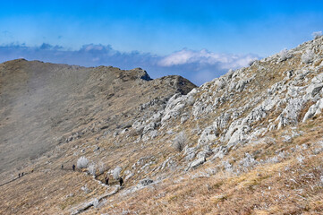 Mountain hikers on a winding trail along a rocky ridge