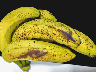 Several bananas held and placed on a table. The peel of this fruit is damaged by the passage of...