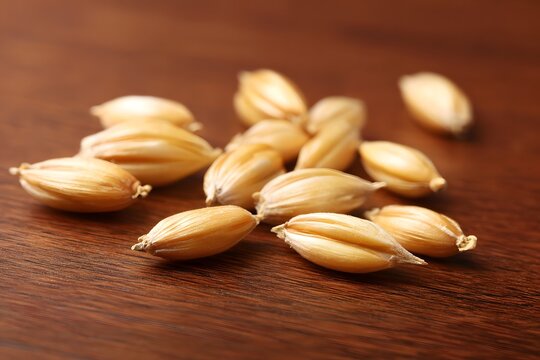 A small pile of whole barley grains on a wooden table.