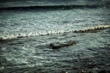 Ocean waves rolling over rocks on a calm coastal shore