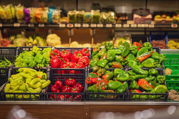 Fresh green and red bell peppers neatly arranged in plastic crates at grocery store produce section. Concept of healthy food, bell peppers, vegetables and supermarket shopping