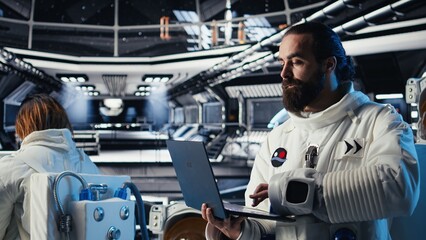 Astronauts in advanced technology spacecraft working together to update red planet updating flight log during routine mission check. Orbit station crew colleagues looking at system diagnostics © DC Studio