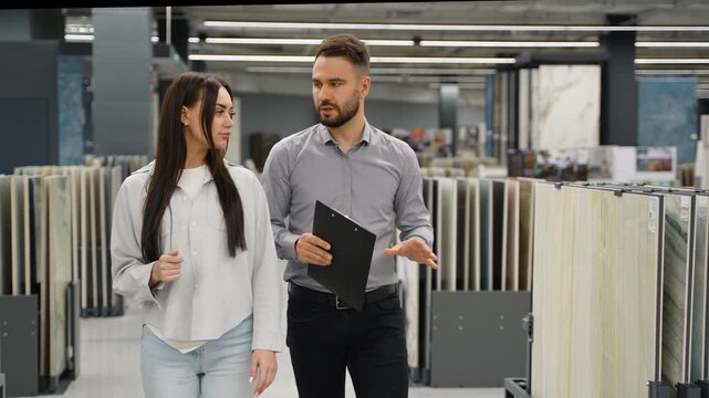 Salesman helping female customer choose tiles in a hardware store