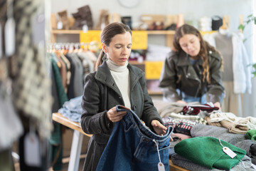 Adult woman buyer choosing jeans in clothing store