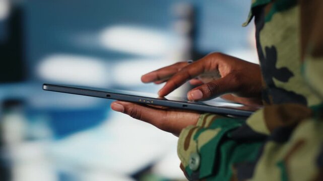 Close up of army soldier using tablet radar software to track hostile threats. African american woman in command center using target acquisition tech on device to detect enemy location
