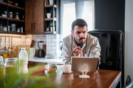 Man having serious video call in kitchen