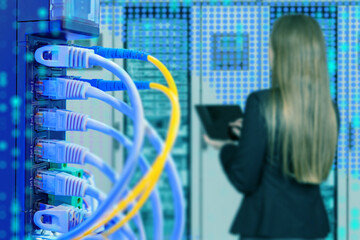 Network cables connected to server rack with female IT specialist working on laptop in data center, concept of cloud computing, cyber security and technology. IT.