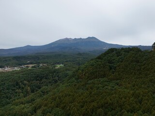 A mountain range with a cloudy sky in the background. The mountains are covered in trees and the sky is overcast