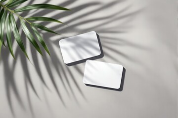 Two blank business cards lie on a light textured surface with palm leaf shadows cast across, creating a tropical sunlight concept for creative design. Ai generative