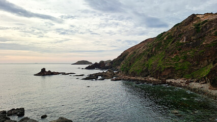 Dramatic Coastal Landscape With Rugged Cliffs Meeting The Sea Under A Cloudy Sky At Sunrise