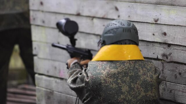 Paintball game, team in camouflage protective uniform with paintball guns and ammunition, strikeball arena battlefield, paintballer aiming and shooting at opponents, airsoft players match tournament