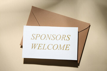 Paper with phrase Sponsors Welcome and envelope on dark beige background, top view