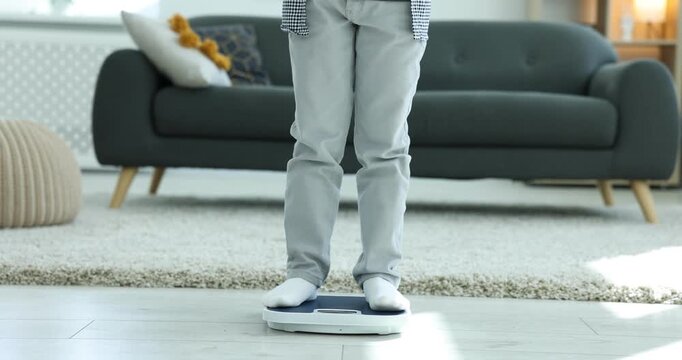 Little boy measuring his weight on scales at home, closeup