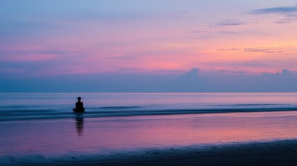 Person in meditation pose on beach during sunset