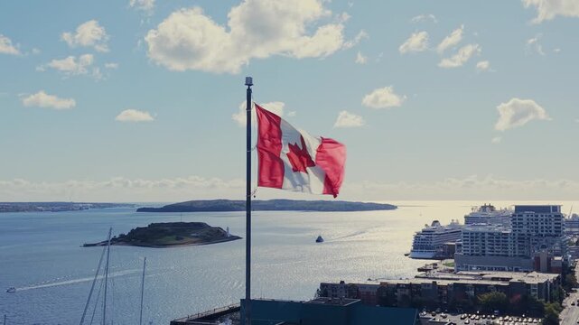 From A High Perspective, The Canada Flag Is Seen Flying Proudly Over Halifax Harbor And Urban Landscape In Nova Scotia. Perfect Shot Representing Canadian Identity And Maritime Pride.