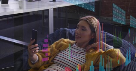 Remote worker in loft lounge lifting smartphone revealing floating financial data analyzing trends - Powered by Adobe