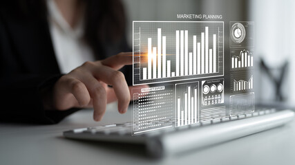 Businesswoman using keyboard to interact with digital marketing data visuals in modern office environment, emphasizing analytics and strategic planning. Impute
