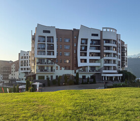 Newly constructed residential building sits in a lush green area with mountains in the background