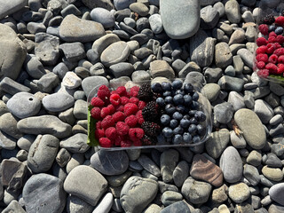 Colorful berries sit neatly on smooth stones, capturing the essence of a summer beach outing