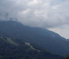 View of a mountain landscape with thick clouds and green forests, capturing a serene atmosphere