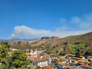 Historic city in Brazil with 18th century buildings with smoke from a forest fire in the background