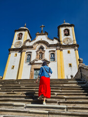 Woman in a red dress climbing the stairs of an 18th-century Portuguese colonial-style church