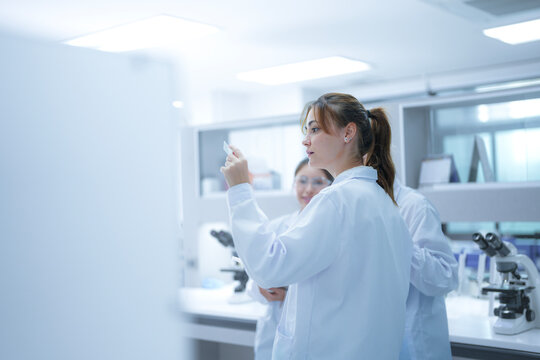 A scientist uses an augmented reality system to share a live microscopic view of a slide with remote colleagues, enabling real-time global consultation and AI-assisted analysis.