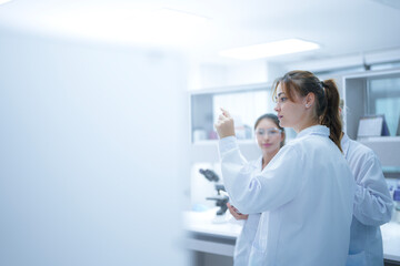 A pathologist presents a challenging case to her colleagues, holding up a histology slide and discussing the cellular morphology to reach a collaborative diagnostic consensus.