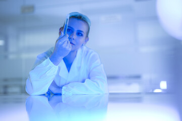 A pharmaceutical chemist inspects the final product of a chemical synthesis, checking the color and clarity of a new liquid drug formulation as part of a quality control check.