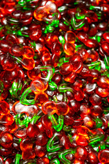 Macro shot of red and green cherry-shaped gummy candies with glossy texture and translucent color showing candy texture and shine.