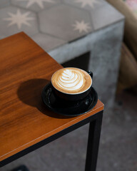 Café latte con arte latte sobre mesa de madera en cafetería moderna