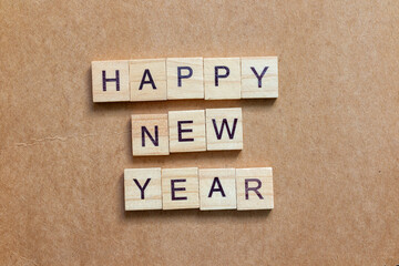 Wooden letter tiles arranged to spell HAPPY NEW YEAR on a brown textured background