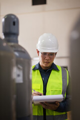 Engineer inspecting SF6 gas cylinders in industrial facility. Focus on safety, pressure container inspection, hazardous material management, and workplace safety checklist documentation