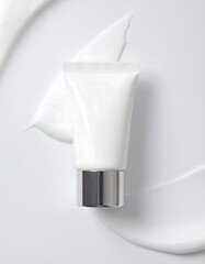 White cosmetic tube on white cream smear background