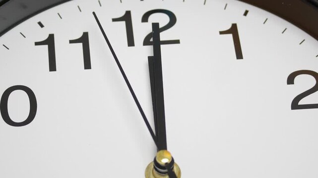 Close-up view clock showing the time at 11:59 with the minute hand approaching midnight, Themes of urgency anticipation countdown and the passage of time.